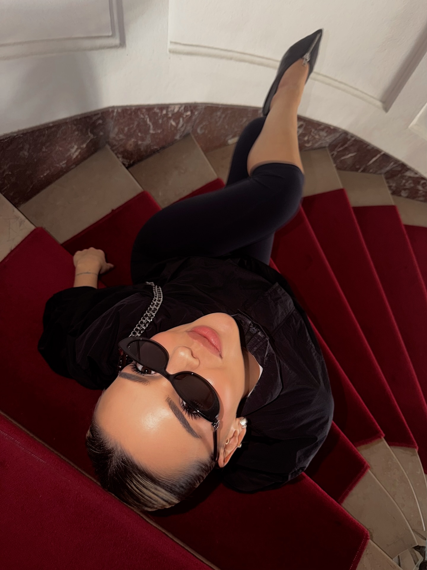 Simla in a dramatic top-down fashion portrait on red velvet stairs