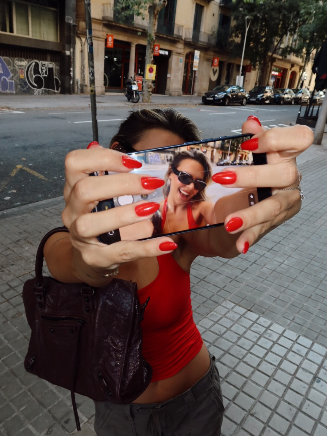 Playful creative portrait of Simla in red holding a phone camera